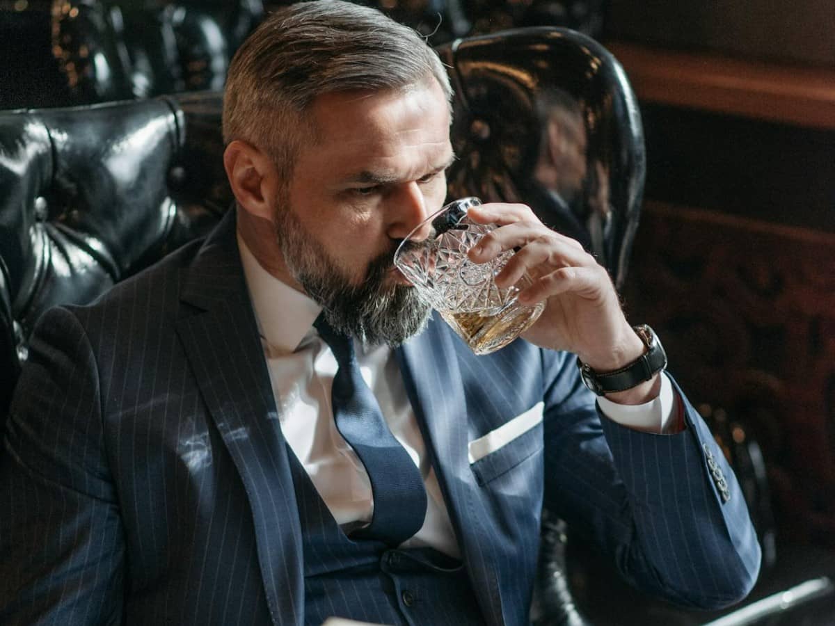 Man drinking a glass of whiskey and read the paper
