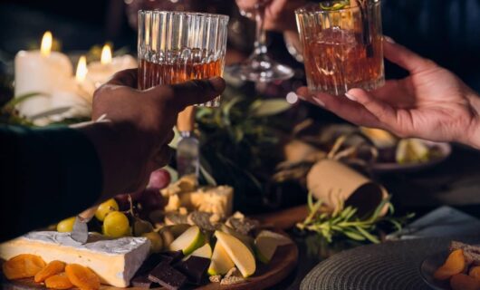 Glasses of whiskey with lots of food in the surroundings