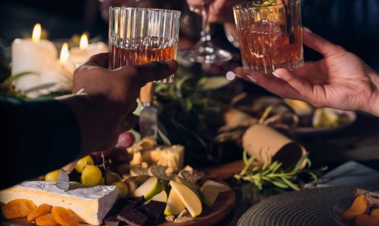 Glasses of whiskey with lots of food in the surroundings