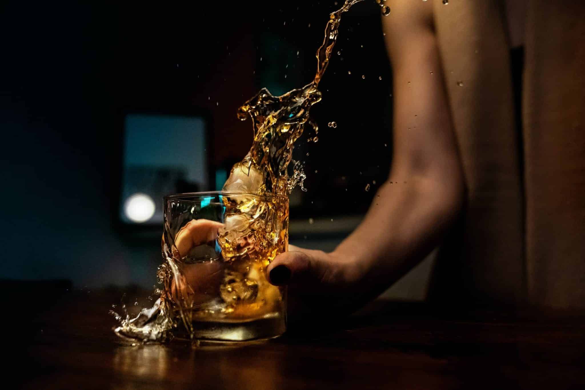 person holding a glass with whisky on the rocks