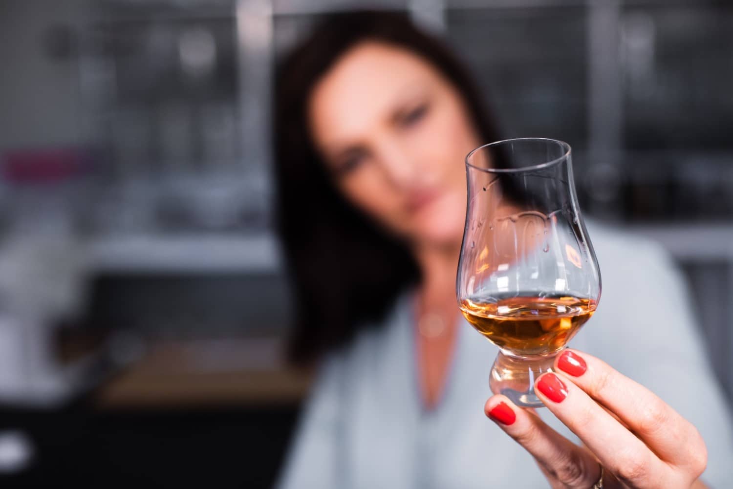 Woman looking at the color and texture of a Scotch Whisky