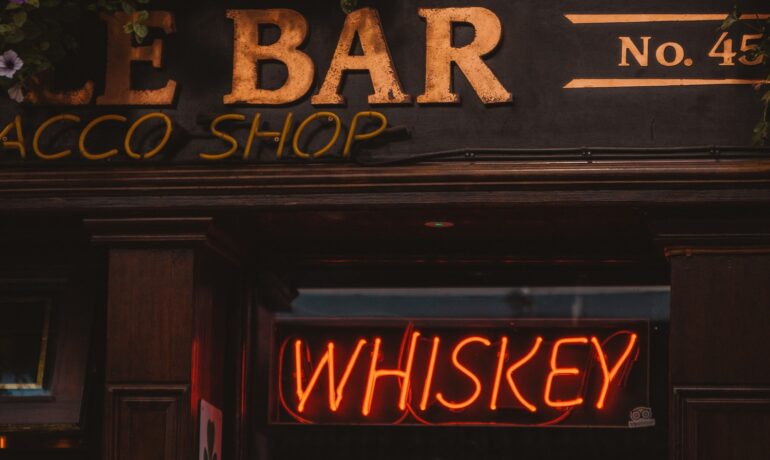 Bar with the word "Whiskey" in neon, where you can enjoy a perfect whisky music list