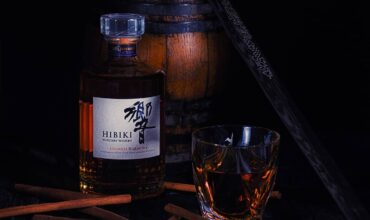 bottle of Suntory's Hibiki Japanese Harmony Whisky near a glass and cinnamon sticks