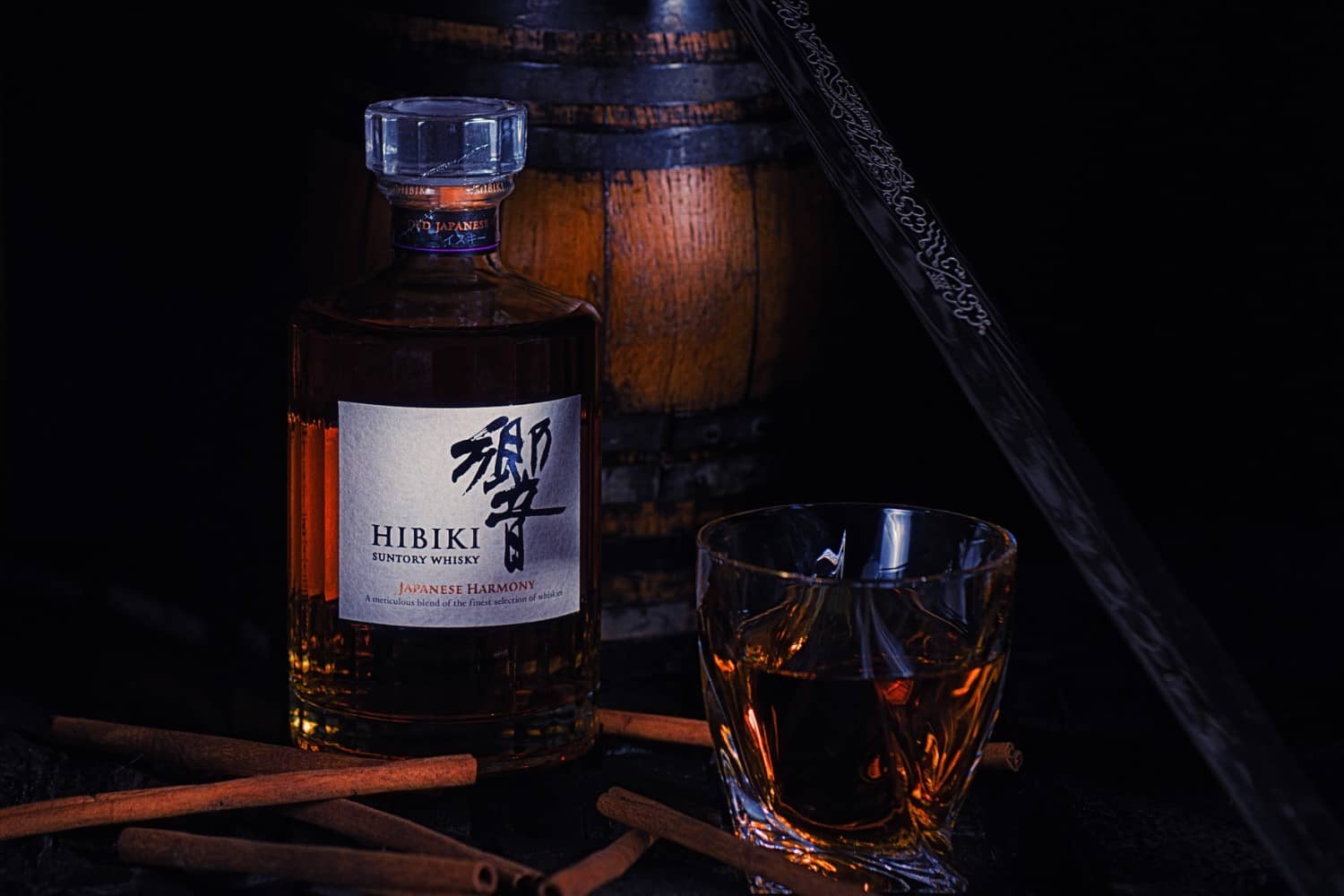 bottle of Suntory's Hibiki Japanese Harmony Whisky near a glass and cinnamon sticks
