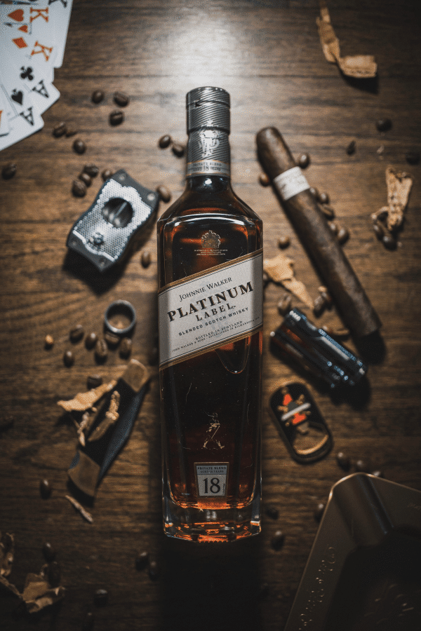 Bottle of Johnnie Walker Platinum 18 years on a table with a cigar and other objects