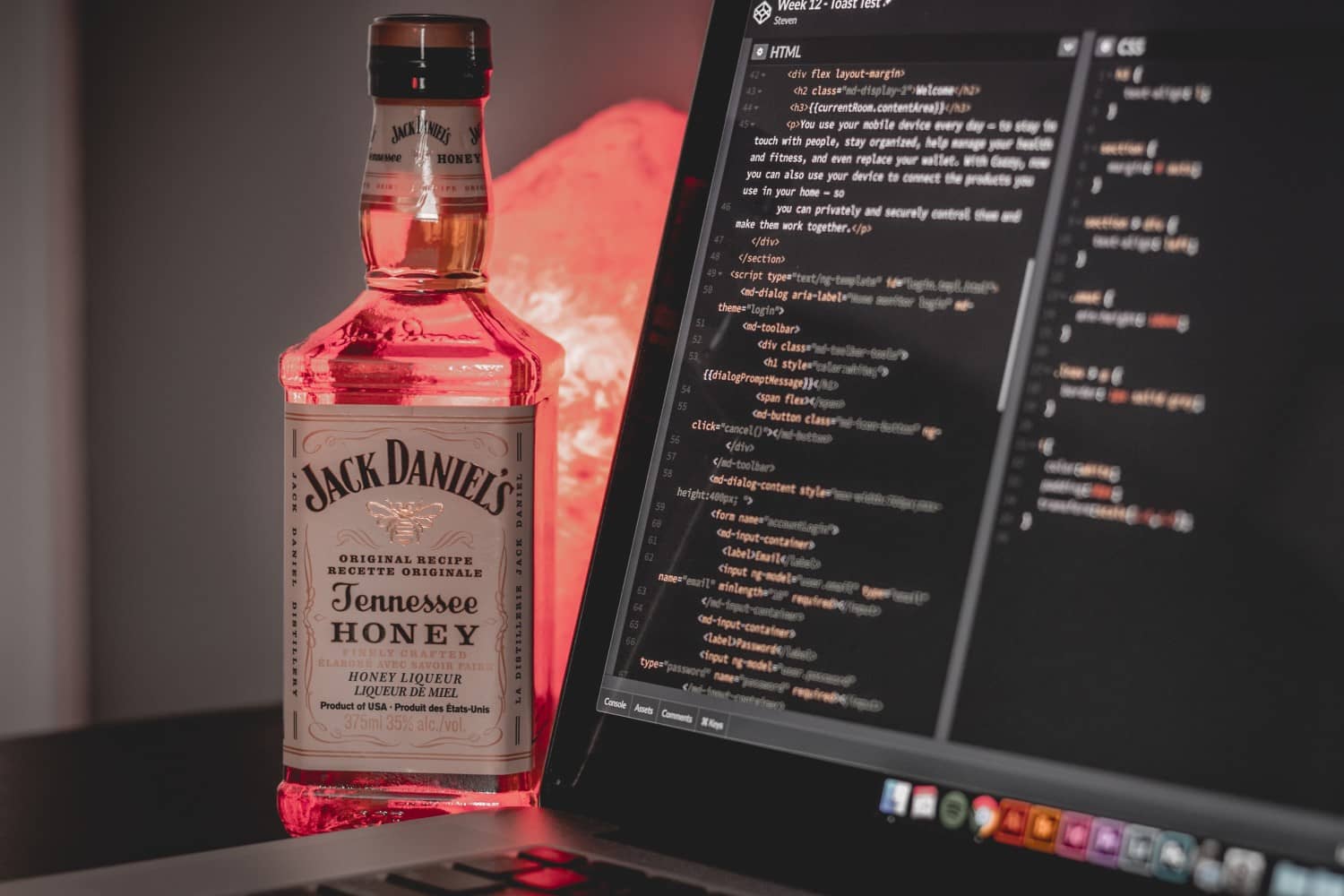 Bottle of Jack Daniels Honey near a computer with html code written